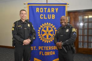 L Sgt. Bellittera and Officer Parker standing in front of a blue banner with gold letters Rotary Club of St. Petersburg FL